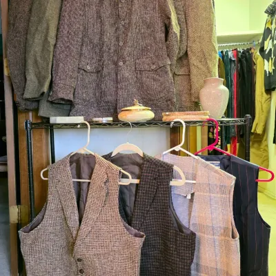 Collection of men's vintage tweed jackets and waistcoats, including a Western-style blazer with faux leather yokes, hanging on a...