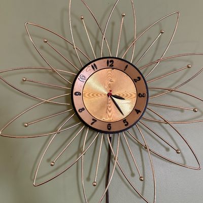 Sale Photo Thumbnail #107: Mid-century modern Lux electric wall clock featuring a gold-toned starburst or flower petal wire frame with ball accents.