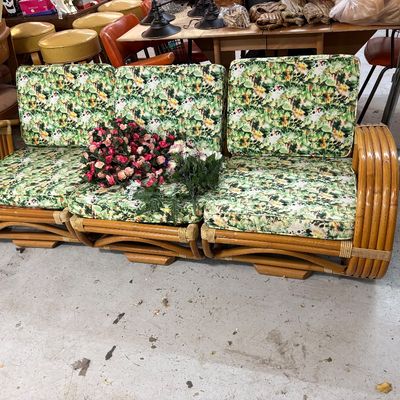 Sale Photo Thumbnail #415: Vintage mid-century three-piece rattan sectional sofa featuring curved arms and green floral patterned cushions.