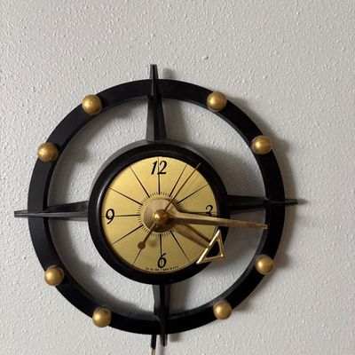 Sale Photo Thumbnail #283: Mid-century modern electric wall clock by Haddon Products, featuring a black compass-style frame with gold-toned accents and hands.