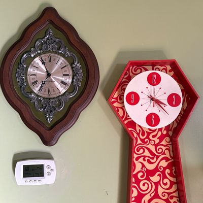 Sale Photo Thumbnail #108: Two vintage wall clocks, including a Seth Thomas clock with an ornate silver-tone bezel on a wooden frame, and a mid-century modern style red clock with a patterned background.