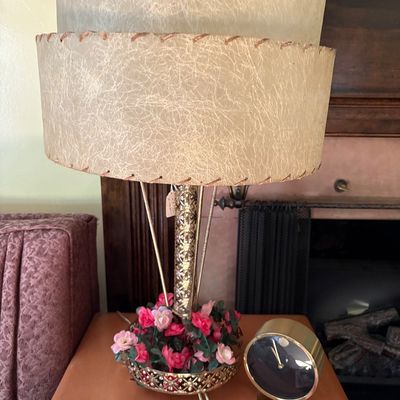 Mid-century modern table lamp featuring a two-tier fiberglass shade, brass-finished base with faux floral accents, shown alongside a...