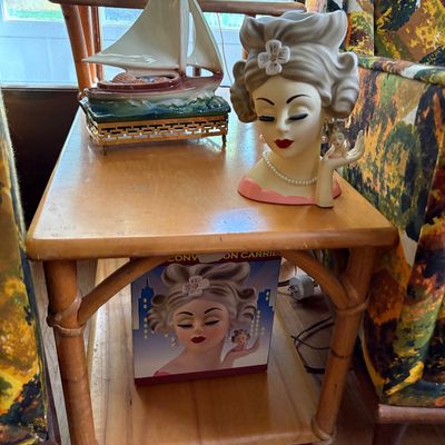 Vintage ceramic lady head vase with pearl necklace and hair flower displayed on a mid-century wooden end table alongside its original box...