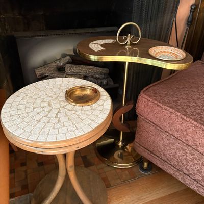 Mid-century modern mosaic tile round side table alongside a kidney-shaped brass and wood smoking stand with built-in ashtray inserts.