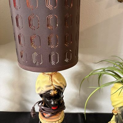 Sale Photo Thumbnail #289: Vintage mid-century ceramic black bust lamp featuring a turbaned figure, complete with a tall brown cutout shade and a black wire tripod base.