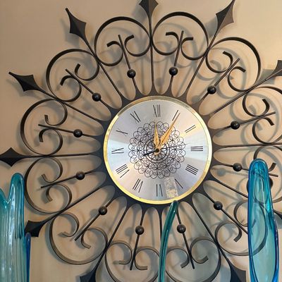 Sale Photo Thumbnail #197: Mid-century modern Elgin wall clock featuring a black wrought iron scrollwork starburst frame and a silver-toned face with Roman numerals.