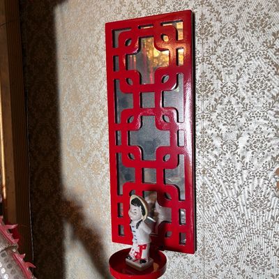Vintage Chinoiserie red lacquered wall sconce with a mirrored back and a small ceramic figurine on the candle holder tray.