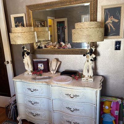 Vintage French Provincial style double dresser in off-white with gold accents, paired with a matching gold-framed wall mirror and a pair...