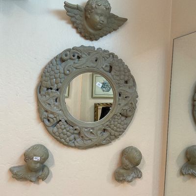 Vintage plaster wall mirror with an ornate grape and leaf motif frame, accompanied by three matching cherub wall plaques.