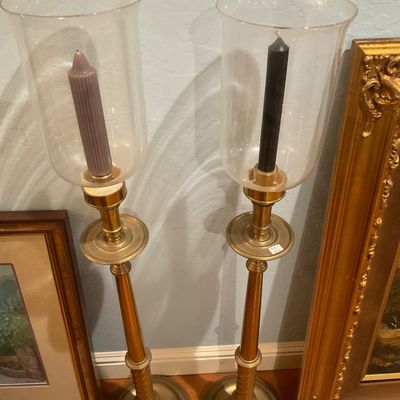 Pair of tall brass candlestick holders with clear glass hurricane shades, featuring a classic traditional style.