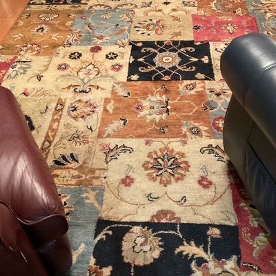 Large area rug featuring a patchwork design of traditional floral and botanical motifs in a warm, multi-colored palette.