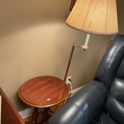 Vintage brass swing-arm floor lamp with a pleated fabric shade, attached to a small round wooden side table.