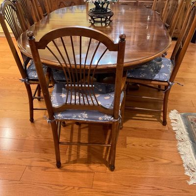 Traditional oak dining set featuring an oval extension table and 8 high-back Windsor-style chairs with rush seats. 