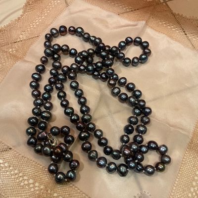 Long strand of knotted black pearls with iridescent green and purple overtones. 