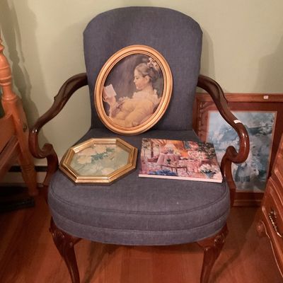 Vintage Queen Anne style armchair with blue upholstery and carved cabriole legs, displaying an oval framed print of a reading woman and...