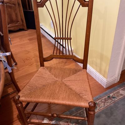 Vintage wooden dining chair featuring a fan-back spindle design, finial accents, and a woven rush seat.