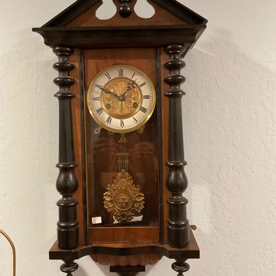 Antique Vienna regulator-style wall clock featuring a walnut case with ebonized pillars, an ornate brass pendulum, and a white dial with...