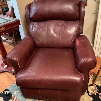 Burgundy leather recliner armchair featuring a plush, segmented backrest and rolled armrests.