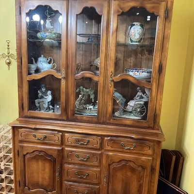 French Provincial style wooden hutch and buffet featuring glass-front display cabinets, brass hardware, and carved details.