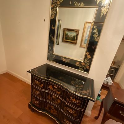 Chinoiserie-style black lacquered commode with gold-painted details and a matching wall mirror featuring floral and butterfly motifs.