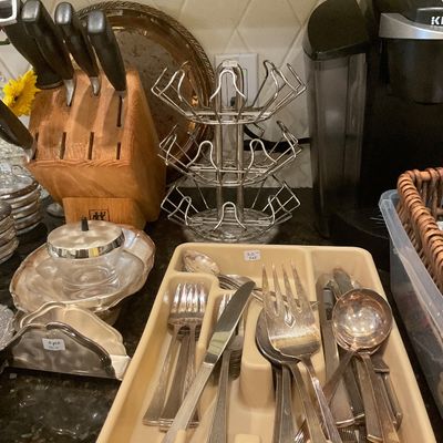 Assorted kitchenware including a silver-plated flatware set in a plastic tray, a wooden knife block.