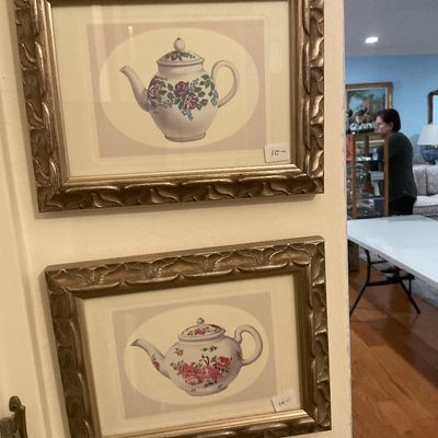 Pair of framed teapot prints featuring floral designs, housed in matching ornate gold-finished frames.