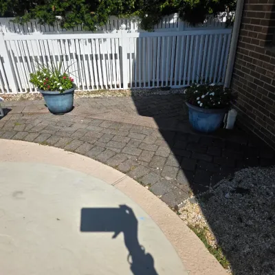 Sale Photo Thumbnail #40: Pair of large blue ceramic planters with flowering plants, situated on a paved patio next to a brick house and white vinyl fence.