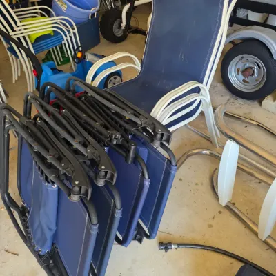 Sale Photo Thumbnail #108: Set of blue folding zero gravity chairs and a stack of white-framed blue mesh patio lounge chairs in a garage setting.