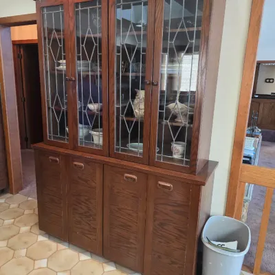 Sale Photo Thumbnail #49: Vintage oak hutch featuring leaded glass upper cabinet doors and a lower storage base with four wooden doors, circa late 20th century.