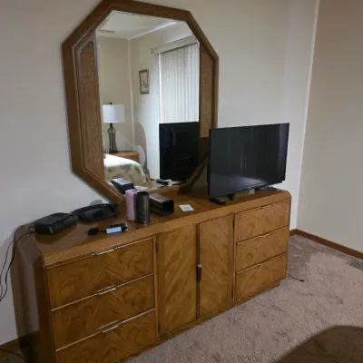 Sale Photo Thumbnail #9: Vintage 1980s oak dresser with a matching octagonal mirror, featuring brass-tone drawer pulls and a central cabinet.