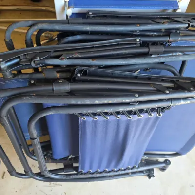 Sale Photo Thumbnail #106: Pair of folded blue zero gravity lounge chairs with black metal frames, showing some wear and minor rust.