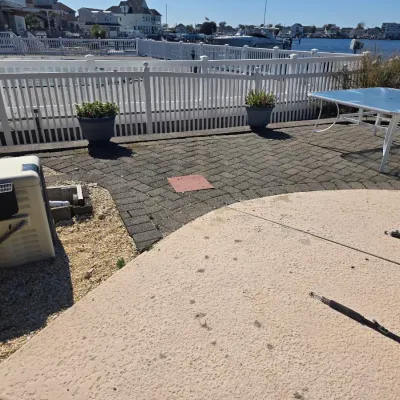 Sale Photo Thumbnail #36: White metal outdoor patio table with a glass top, shown alongside a pool heater and potted plants on a paved patio overlooking a canal.