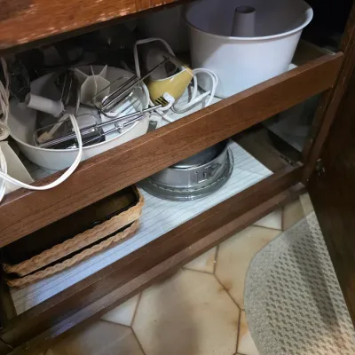 Sale Photo Thumbnail #64: Assorted kitchen baking items stored in a wooden cabinet, including a vintage hand mixer, a bundt pan, and a springform pan.