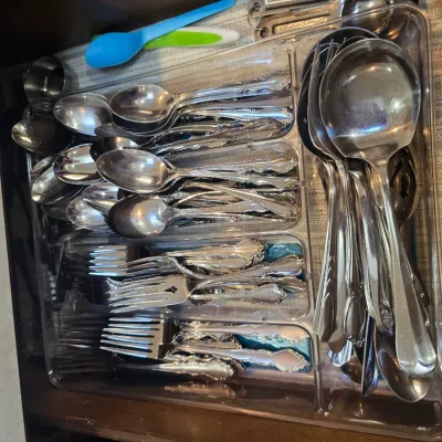 Sale Photo Thumbnail #66: Assorted stainless steel flatware set featuring ornate floral handles, organized in a clear plastic drawer tray.
