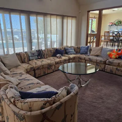 Sale Photo Thumbnail #3: Large vintage modular sectional sofa with tropical bamboo-patterned upholstery, paired with a circular glass-top coffee table on a chrome base.