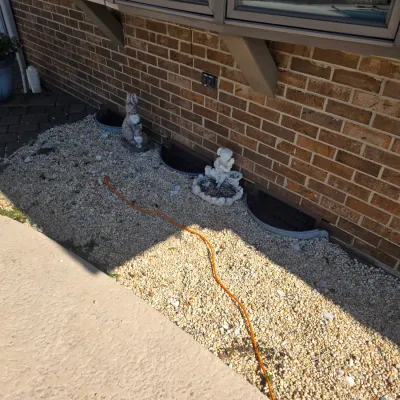 Sale Photo Thumbnail #38: Assorted concrete garden statues, including a rabbit and a cherub, displayed in a gravel bed alongside a brick house.