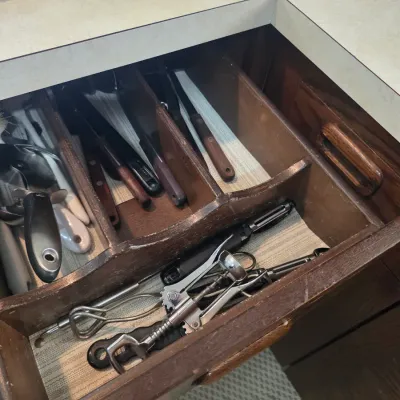 Sale Photo Thumbnail #68: Assorted kitchen utensils, including knives, a corkscrew, and peelers, organized inside a vintage wooden drawer divider.