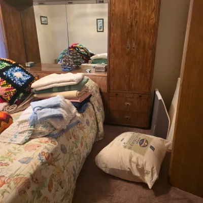 Sale Photo Thumbnail #79: Vintage 1980s oak bedroom wall unit featuring a mirrored headboard bridge, integrated lighting, and a matching wardrobe cabinet with drawers.