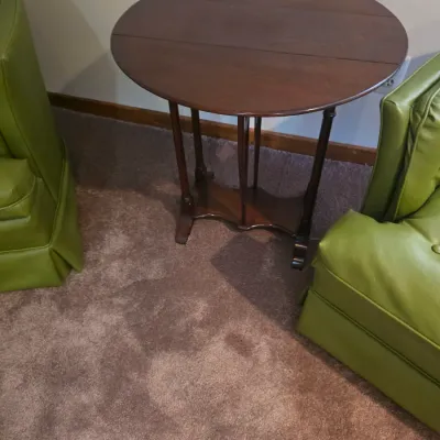 Sale Photo Thumbnail #119: Vintage dark wood drop-leaf gateleg side table, flanked by two mid-century green vinyl armchairs.