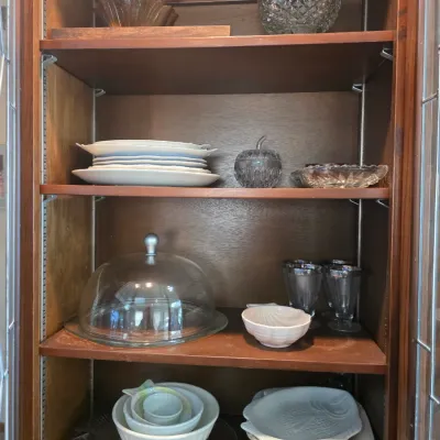 Sale Photo Thumbnail #51: Assorted vintage glassware and ceramic serving dishes, including a glass cake dome, nesting bowls, and cut glass bowls, displayed inside a wooden hutch.