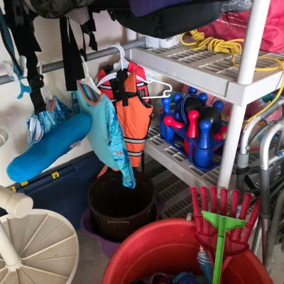 Sale Photo Thumbnail #90: Assorted outdoor and recreational gear, including children's life jackets, a plastic toy bowling set, buckets, and mobility walkers stored on shelving.