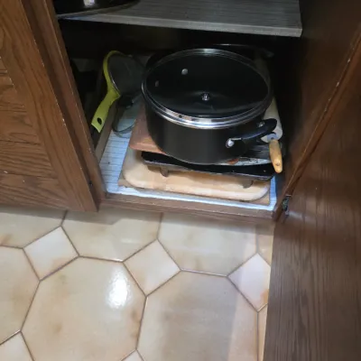 Sale Photo Thumbnail #71: Assorted kitchenware stored in a wooden cabinet, including a black non-stick pot with lid, wooden cutting boards, and a rolling pin.