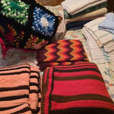 Sale Photo Thumbnail #83: Assortment of vintage handmade crochet blankets and afghans in various patterns and colors, including granny square, chevron, and striped designs.
