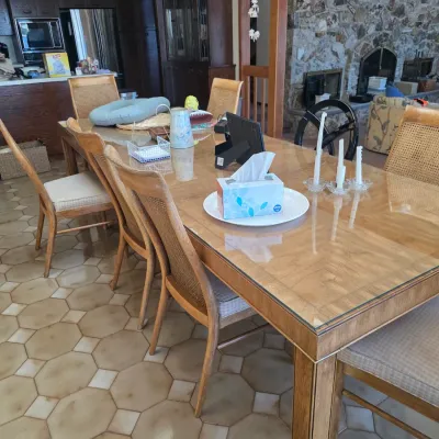 Sale Photo Thumbnail #45: Mid-century modern dining set featuring a large rectangular wooden table with a glass top protector and matching cane-back chairs with upholstered seats.