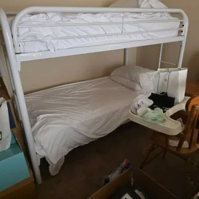 Sale Photo Thumbnail #77: White metal twin-over-twin bunk bed frame with integrated ladder and safety rails, shown with white bedding.