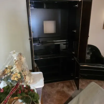 Sale Photo Thumbnail #122: Contemporary black lacquer media armoire with bi-fold upper doors and lower cabinet storage, shown alongside holiday decor and a black leather armchair.