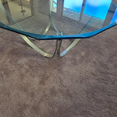 Sale Photo Thumbnail #129: Mid-century modern coffee table featuring a thick, octagonal glass top with beveled edges resting on a curved chrome base.