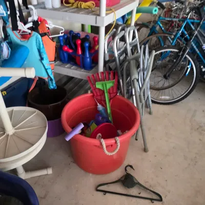 Sale Photo Thumbnail #89: Assorted garage items including a red plastic tub with toys, a white PVC stand, life jackets, folding walkers, and several bicycles.