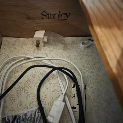 Sale Photo Thumbnail #10: Interior drawer of a Stanley Furniture piece, featuring a branded logo stamp, patterned liner, and integrated power outlet with cords.