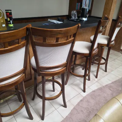 Sale Photo Thumbnail #15: Set of four contemporary wooden swivel barstools with upholstered backs and seats, lined up along a home bar.